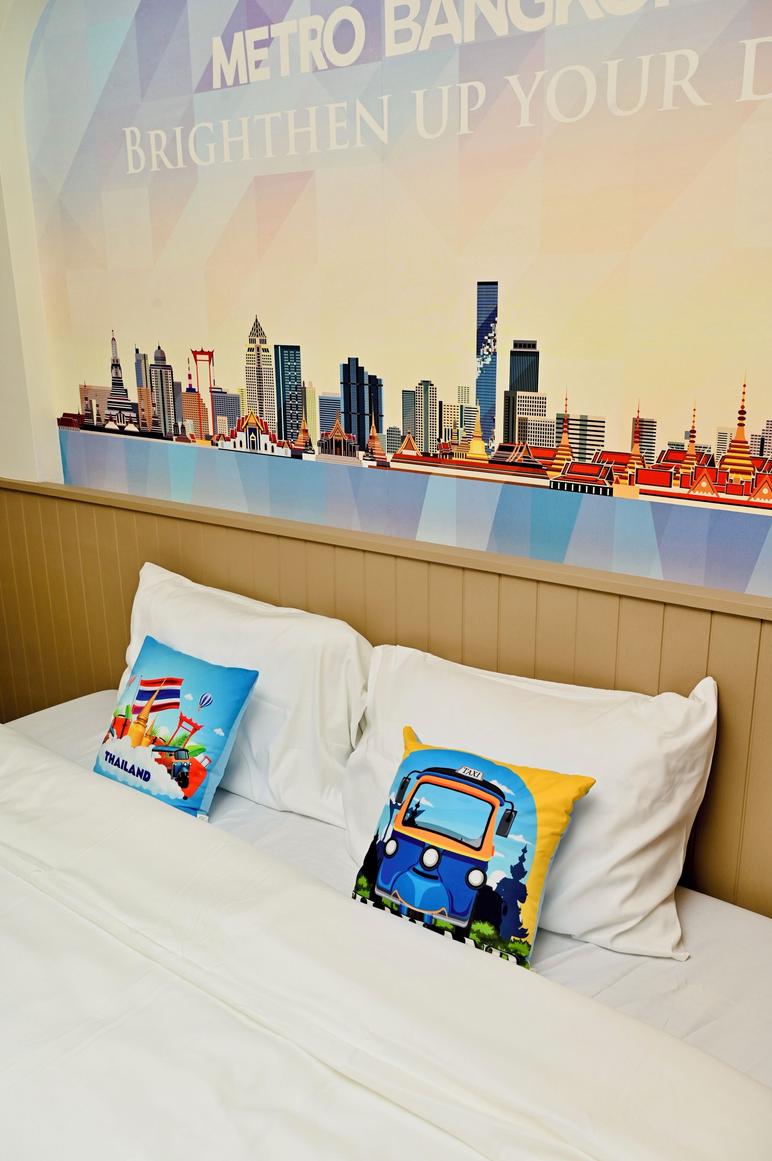 A hotel room with a bed, two pillows, and a wall mural of a city skyline.
