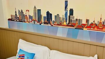 A hotel room with a bed, two pillows, and a wall mural of a city skyline.