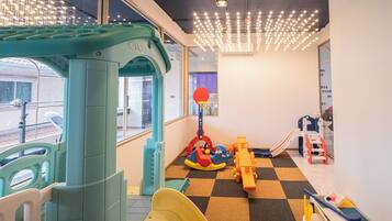 Un espace de jeux pour enfants avec un toboggan, des structures d’escalade et une piscine à balles.