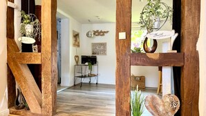 A wooden-framed doorway with hanging plants, a heart-shaped decoration, and a small potted plant on the floor.