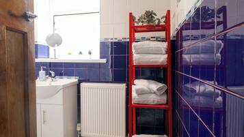 A bathroom with a white sink, a mirror, a red towel rack, and a radiator.