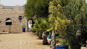 A courtyard with a stone wall, potted plants, and a palm tree. - Welcome to Villa Fatima - Your haven of tranquility (Ghazoua)