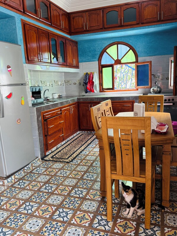 A kitchen with wooden cabinets, a refrigerator, a stove, and a dining table with chairs.