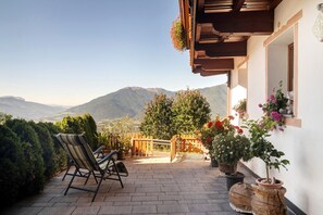 Eine Terrasse mit Blick auf Berge, einer Holzbank und Kübelpflanzen.