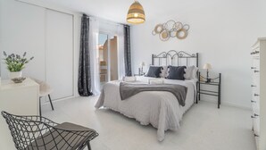 A bedroom with a bed, bedside tables, a hanging light fixture, a chair, and a potted plant. - 'Afirama 1' Holidays with Sea View, Wi-Fi and Air Conditioning (Las Caletillas)