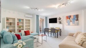 A modern living room with a sofa, coffee table, dining area, and a flat-screen TV mounted on the wall. - 'Afirama 1' Holidays with Sea View, Wi-Fi and Air Conditioning (Las Caletillas)