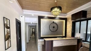 Een moderne receptie met een houten plafond, een kroonluchter, een receptiebalie en een bank.