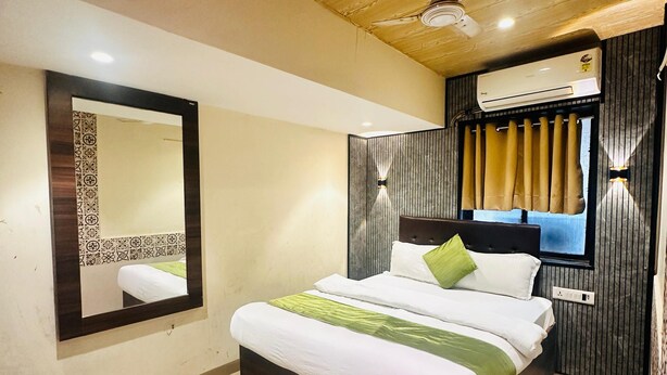 Een moderne hotelkamer met een groot bed, een plafondventilator, een airconditioning en een grote spiegel.