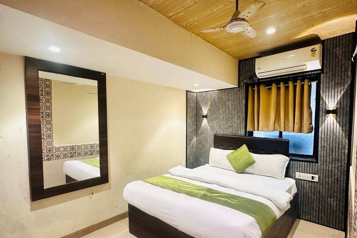 Une chambre d’hôtel moderne dotée d’un grand lit, d’un ventilateur de plafond, d’un appareil de climatisation et d’un grand miroir.
