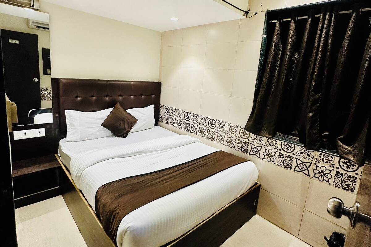 Une chambre d’hôtel avec un lit, un ventilateur de plafond, une salle de bain avec un rideau de douche et un mur carrelé.