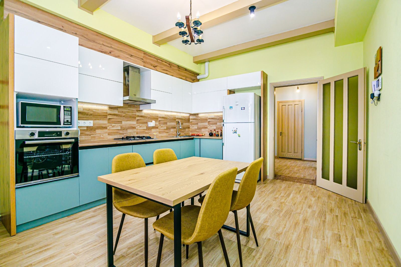 A compact kitchen with a wooden table and chairs, a microwave, oven, and a refrigerator.