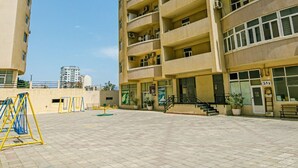 Un edificio residencial de varios pisos con balcones, un patio empedrado y cielo despejado.