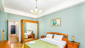 Un dormitorio con cama, mesitas de noche, un espejo y una araña.