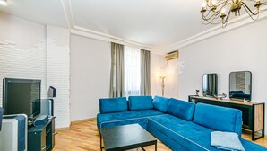 Una sala de estar moderna con un sofá modular, una mesa de centro, un televisor y una araña.