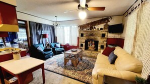 Un salon chaleureux avec une cheminée, un canapé, une table basse et un téléviseur fixé au mur.