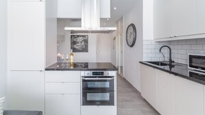 Eine moderne Küche mit weißen Schränken, einer schwarzen Arbeitsplatte, einem eingebauten Backofen und einer Edelstahl-Dunstabzugshaube.