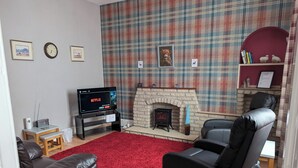 A living room with a fireplace, a television, and two leather sofas. - Cozy one Bedroomed House in Aberchirder (Huntly)