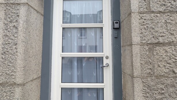 A white-framed door with a small mailbox at the bottom, set in a stone wall. - Cozy one Bedroomed House in Aberchirder (Huntly)