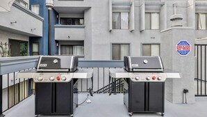 Un moderno edificio de apartamentos con balcón que cuenta con dos parrillas Weber.