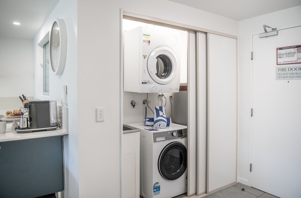A laundry room with a washing machine, dryer, and a small countertop with a coffee machine and a bowl.