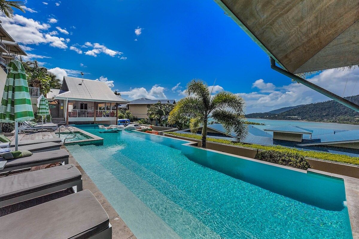A swimming pool with lounge chairs and a building in the background.