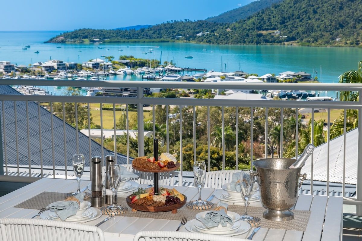 A table set for dining with a view of a marina and boats.