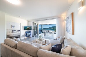 Ein modernes Wohnzimmer mit einer Couch, einem Couchtisch und Blick ins Freie.