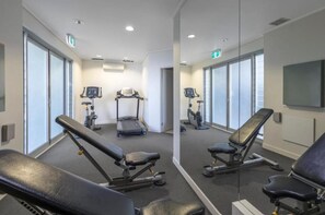 A gym with exercise equipment, including treadmills and weight benches, and large windows.