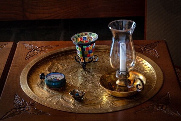 A tray with a decorative glass pitcher, a colorful glass container, and a small blue bowl on a wooden surface with intricate carvings. - Villa Annelies Pelion (Volos)