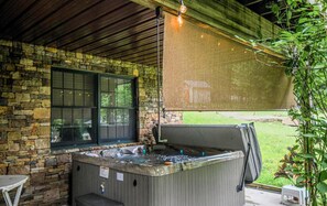 A hot tub in an outdoor setting with a stone wall and a window.