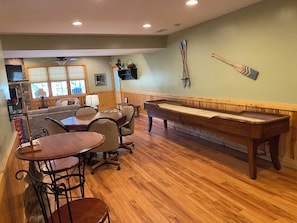 A billiards room with a pool table, chairs, a sofa, and a television.