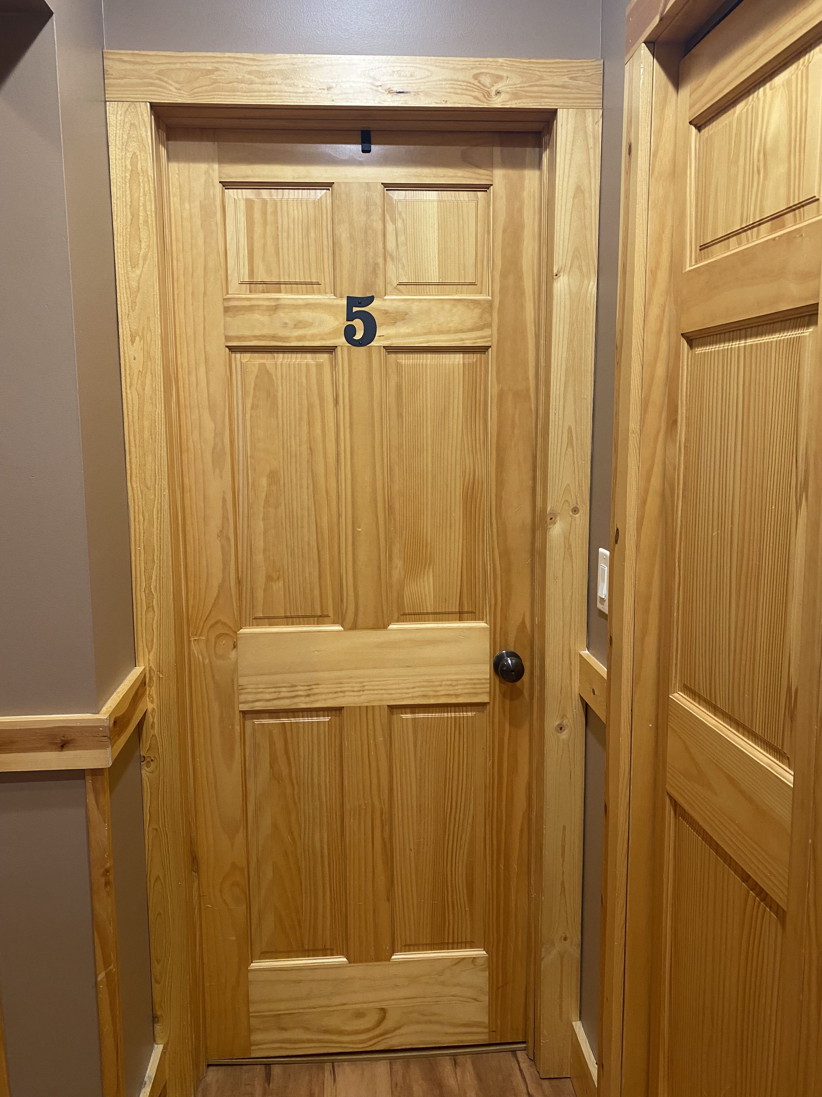 Une porte en bois portant le numéro 5, avec une poignée et un trou de serrure.