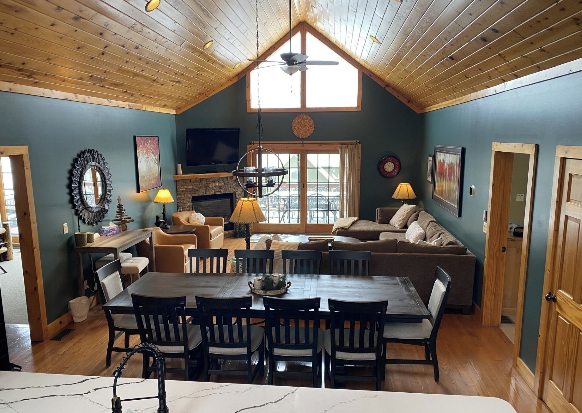 Un salón acogedor con chimenea, una zona de comedor con una mesa y sillas de madera, y un techo alto con vigas a la vista.