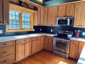 A kitchen with wooden cabinets, a stainless steel microwave, and an oven.