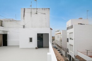 Un toit surmontant un bâtiment blanc, avec une porte noire et une petite fenêtre.