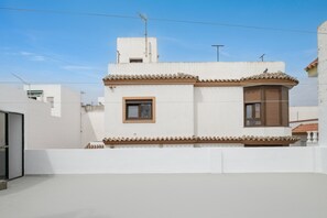 Un bâtiment blanc avec un toit recouvert de tuiles, une petite fenêtre et un balcon.