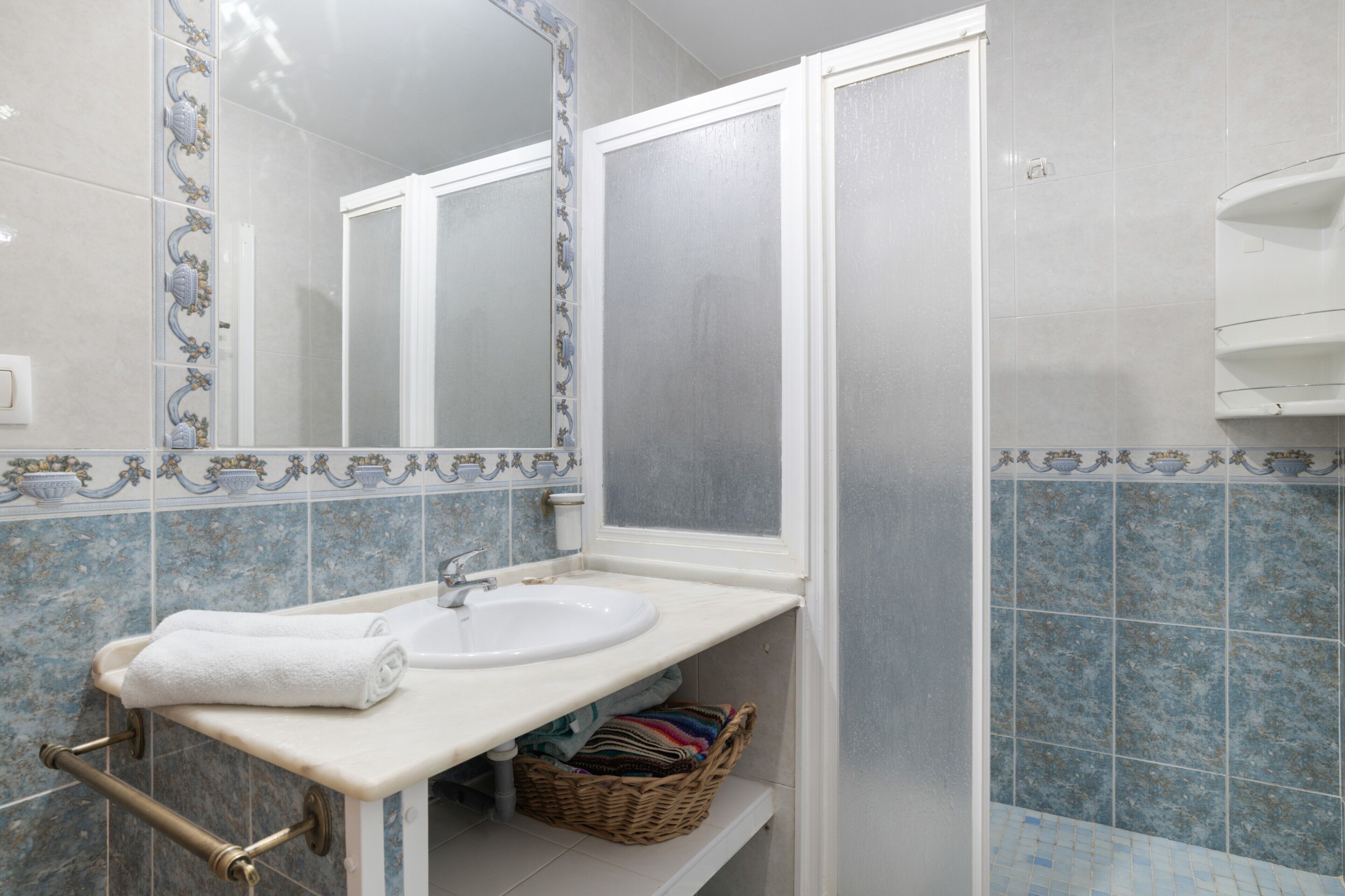 A bathroom with a sink, mirror, and tiled walls.