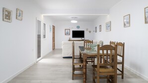 Un pasillo con una mesa de comedor y sillas, un sofá y un televisor de pantalla plana.