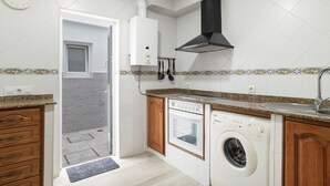 Una cocina equipada con horno empotrado, lavavajillas y lavadora, una ventana y un reloj en la pared.
