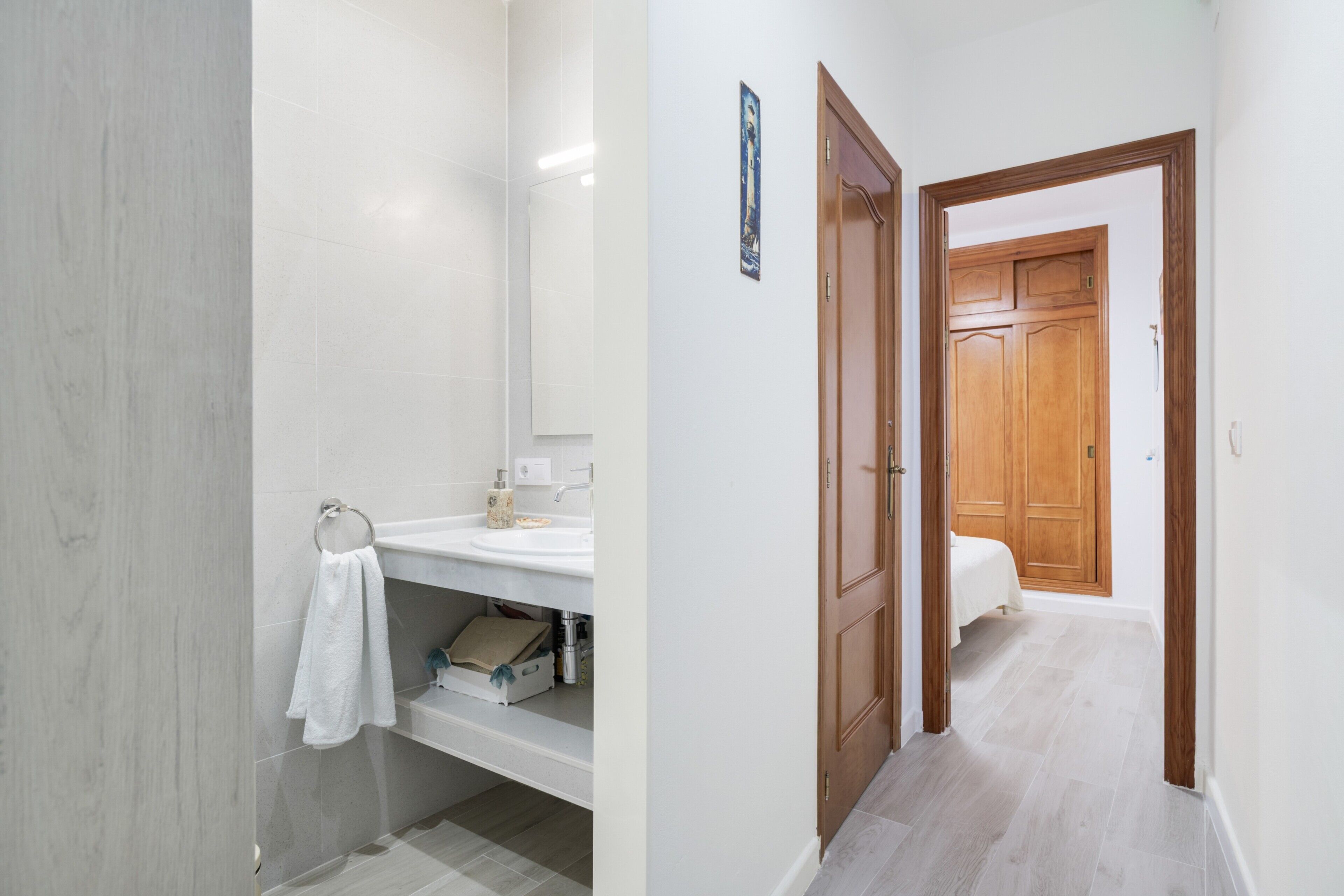 A bathroom with a white sink, mirror, and towel rack.