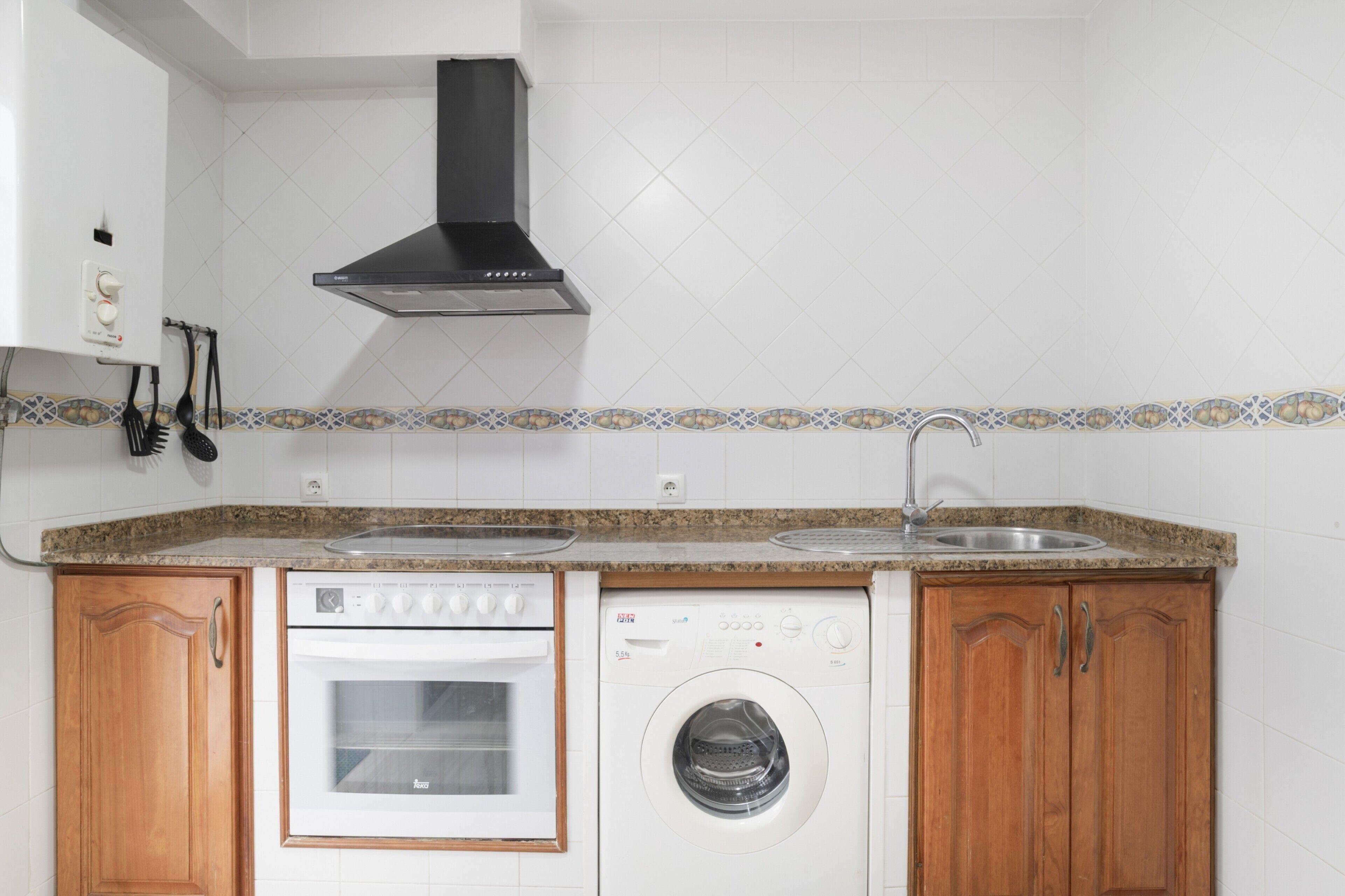 Una cocina equipada con estufa, horno, lavadora y pileta.