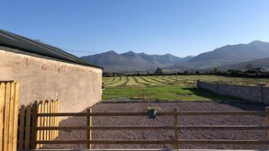 Un paysage rural avec un bâtiment, une zone recouverte de gravier et des champs en arrière-plan.