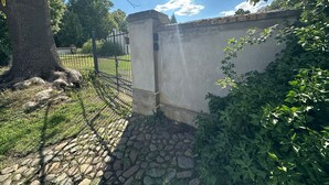 A stone pathway leading to a gated area with a tree and a wall. - Vacation apartment Minkwitz in the nursery house in Fürstlich Drehna (Luckau, OT Fürstlich Drehna)