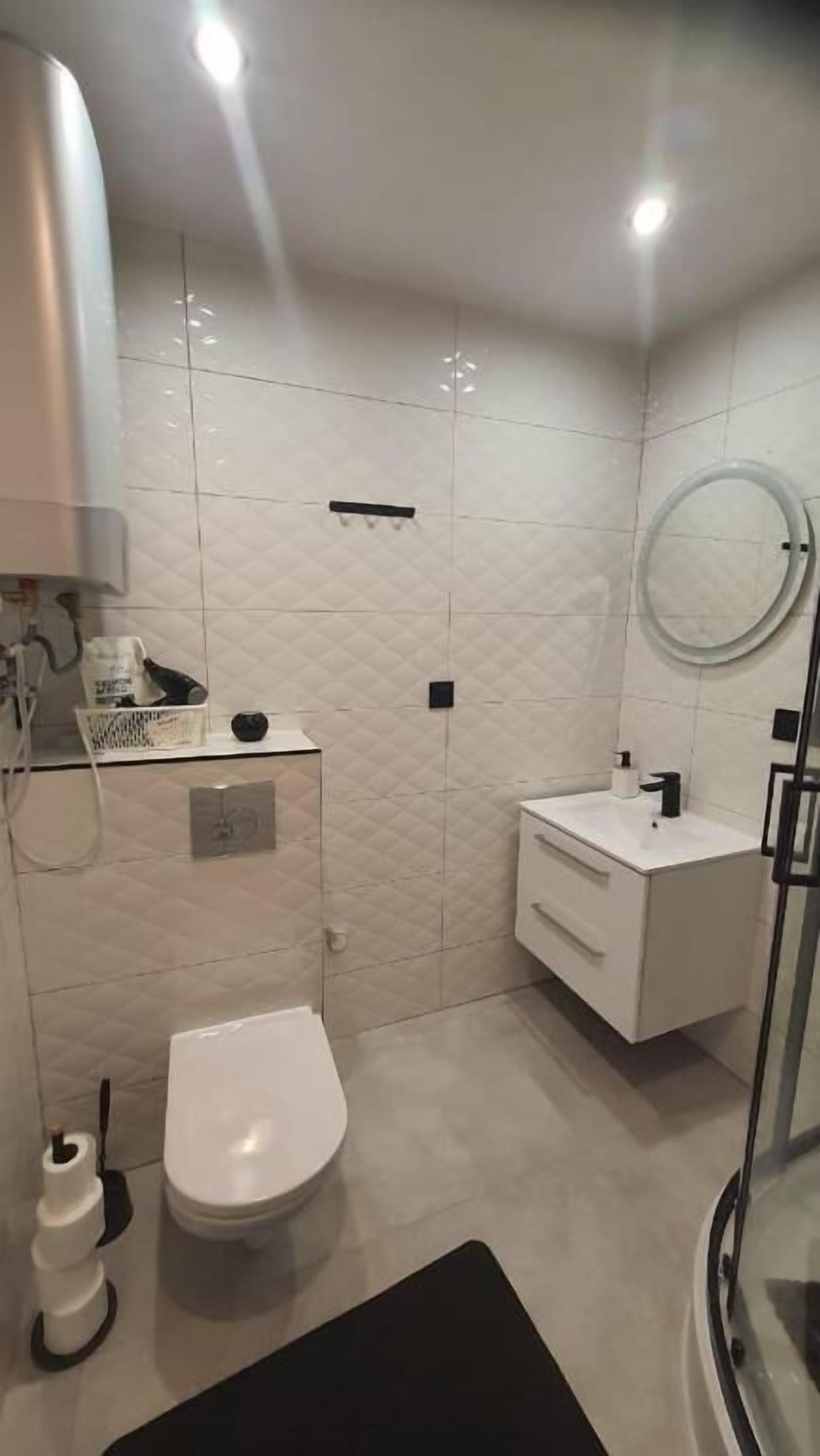 Une salle de bain moderne équipée de toilettes, d’un lavabo et d’une zone douche.