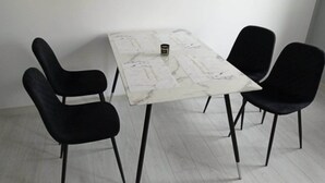A white marble table with a black coffee cup, surrounded by four black chairs in a minimalistic room. - Komfortowy Apartament u Baltazara (Duszniki Zdroj)