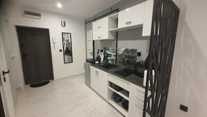 A modern kitchen with white cabinets, a black countertop, and a built-in oven. - Komfortowy Apartament u Baltazara (Duszniki Zdroj)
