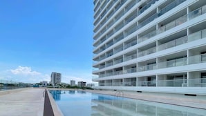 A modern building with a pool, multiple balconies, and a clear sky. - w Luxurious Loft w Balcony in Crespo (Cartagena)