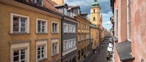 A narrow street lined with historic buildings featuring traditional architecture and a prominent church tower in the background.