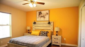 A bedroom with a bed, nightstands, a ceiling fan, and a wall-mounted horse painting.