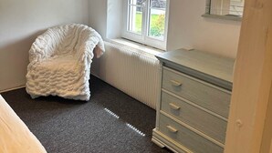 A bedroom with a white radiator, a window with blinds, a white chair, and a dresser. - Mimosa room - Domaine de la Provençale (ST DIDIER DE LA TOUR)